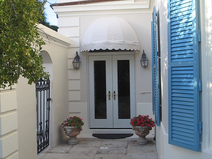 White round awning above white double doors with blue shutters